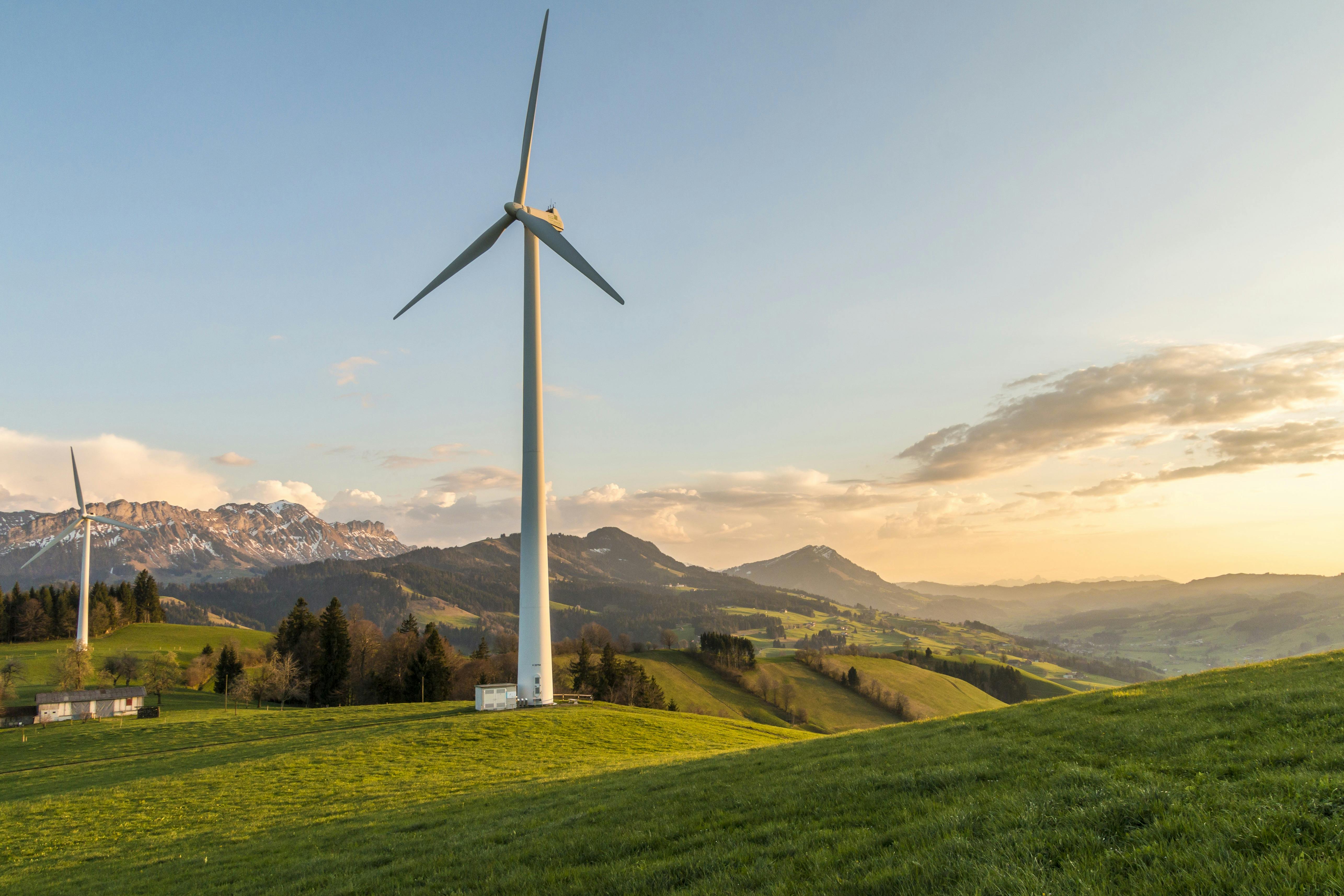 A single wind turbine on an alpine hillside at golden hour